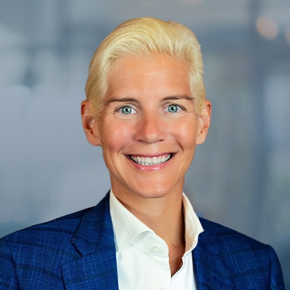Elizabeth Evans Weiss, owner and founder of E2 Roofing, smiling in a professional setting, wearing a blue blazer, representing the company's commitment to quality roofing services and community involvement in Jacksonville.