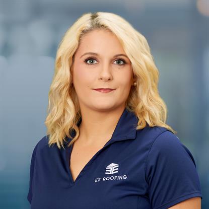 Jamie Rasmussen, Office Manager at E2 Roofing, wearing a branded navy polo shirt, professional portrait with a blurred background.