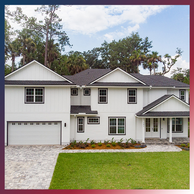 Two-story white home with a black roof, landscaped yard, and driveway, showcasing a modern design suitable for Jacksonville's climate and roofing services.