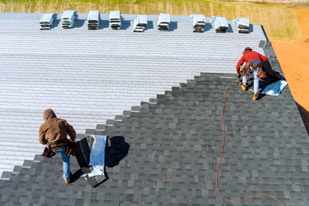 Roofers installing asphalt shingles on a residential roof in Jacksonville, FL.