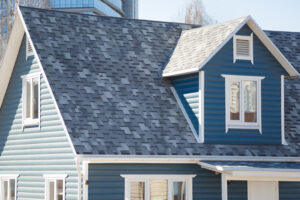 Blue home with a newly installed gray shingled roof maintained by E2 Roofing in Jacksonville